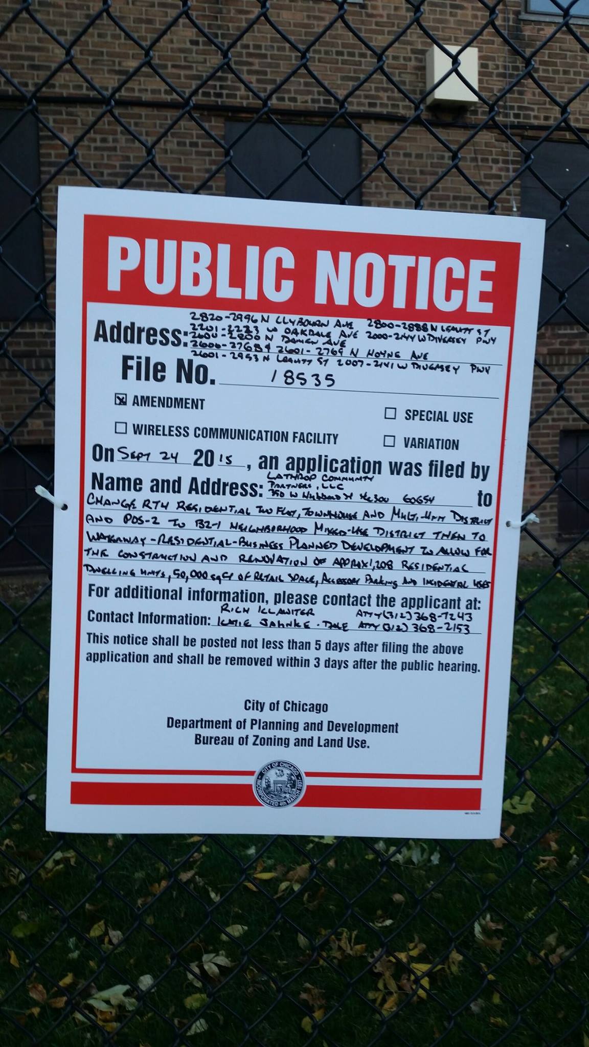 A close up of public notice of an intent to file a zoning change for Lathrop Homes in Chicago, attached to a wire fence