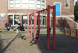 Children play on the swing set on the grounds of Dudley Charter School in Boston, Massachusetts.