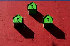 small green birdhouses on red wall