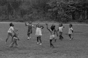 A black and white photo of children playing at New Communities in Georgia, the largest African-American owned parcel of land in the U.S. in the 1960s.