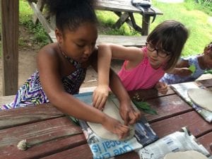 Two young girls sit at a table to work on a community mural project.