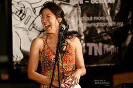 Poet traci kato-kiriyama laughs at the microphone.