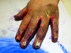 closeup of child's hand doing art, daubed with paint