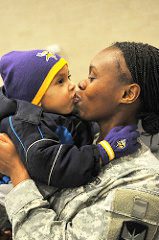 Mother in uniform hugging young child