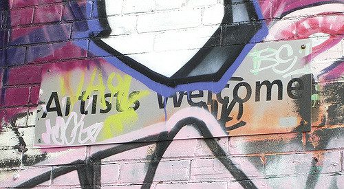"Artists welcome" sign partly obscured by graffiti