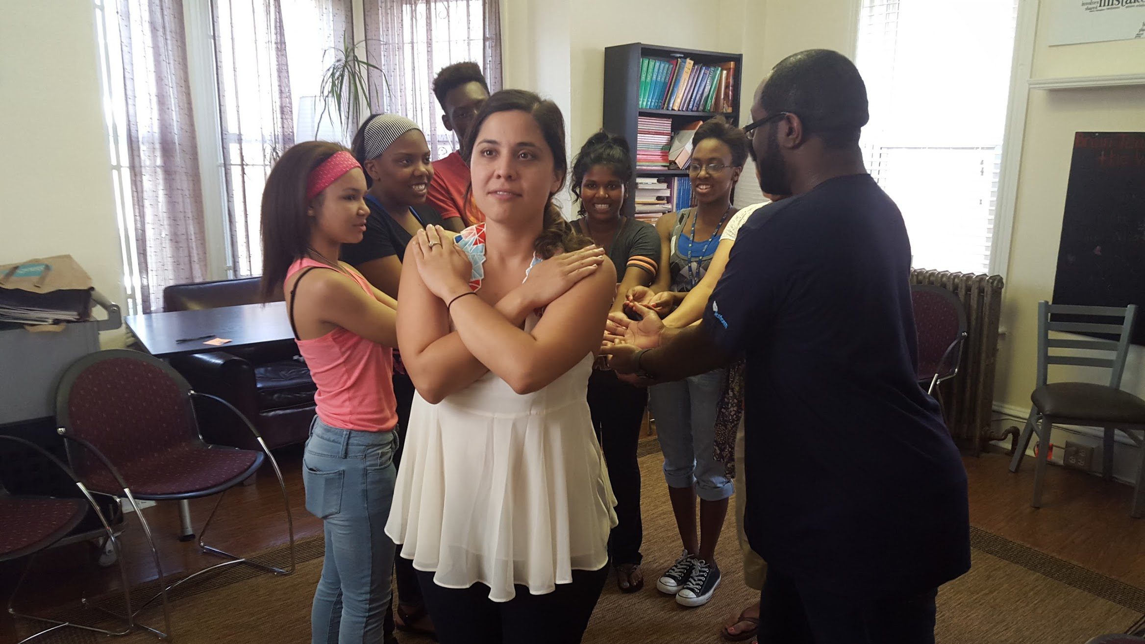 A member of a New Jersey based advocacy group crosses her hands over her chest and her fellow group members line up behind her with their arms extended. This is a trust fall.