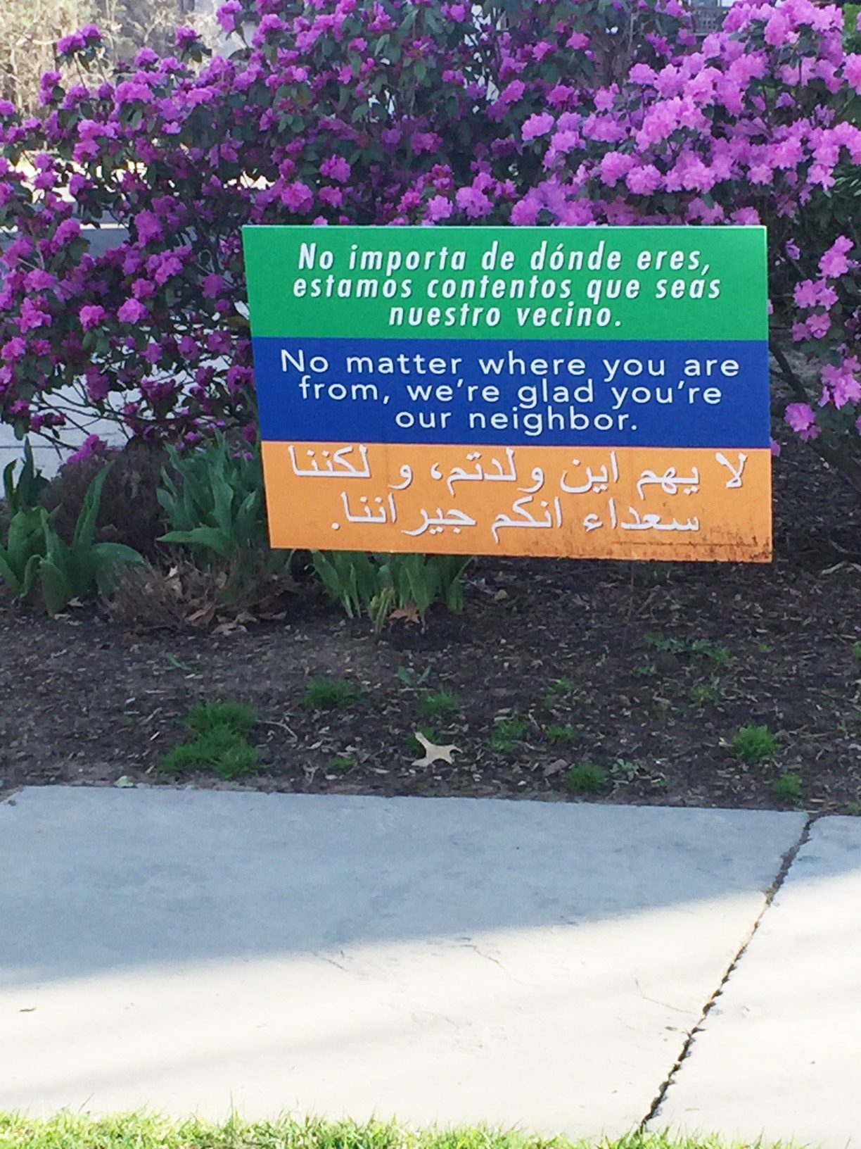 Lawn sign in three languages: We're glad you're our neighbor