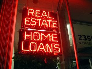 Neon sign in window reads "Real Estate Home Loans."