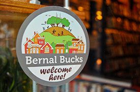 A sticker on a window promotes Bernal Bucks, a business initiative in San Francisco. 